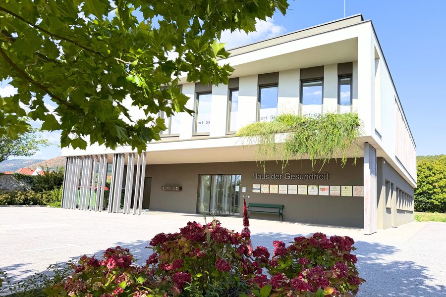Das Haus der Gesundheit in Bad Fischau-Brunn, von Bäumen und Rosen umgeben.